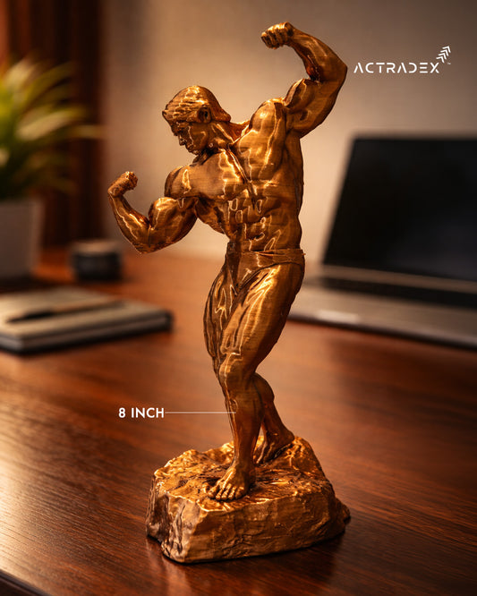 The Arnold Gym Champion - 8” Sculpture is a gold-toned, premium metallic desk piece featuring a muscular bodybuilder—perfect for gym lovers to display near laptops, notebooks, or plants as an inspiring gift.