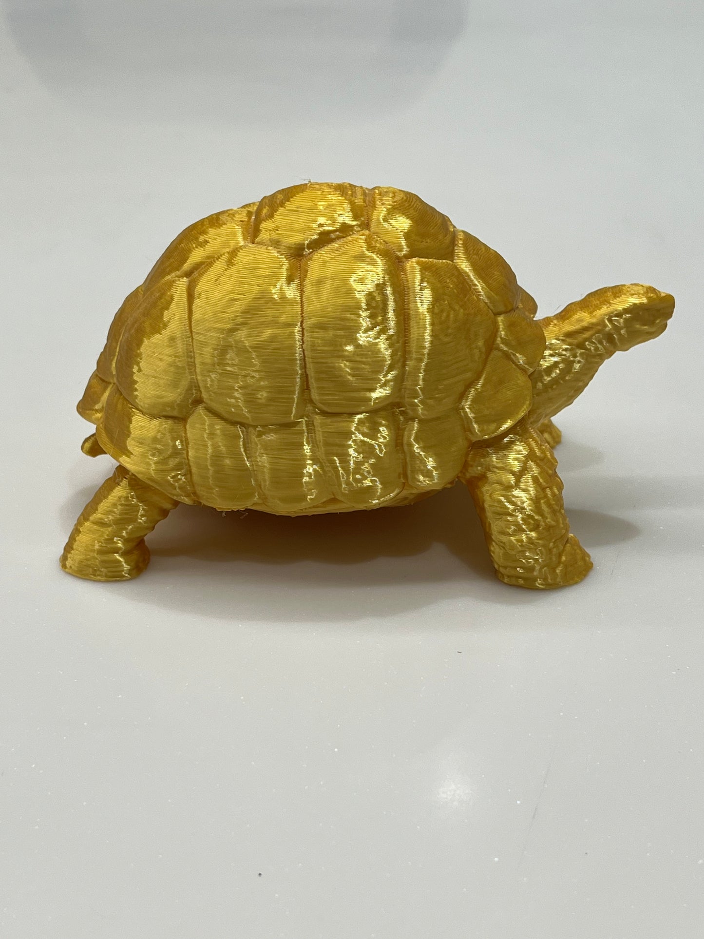 The Golden Vastu Tortoise - 5 Inch Prosperity & Stability Symbol, with a detailed shell and shiny gold finish, is displayed on a plain white surface, representing prosperity as per Vastu Shastra principles.