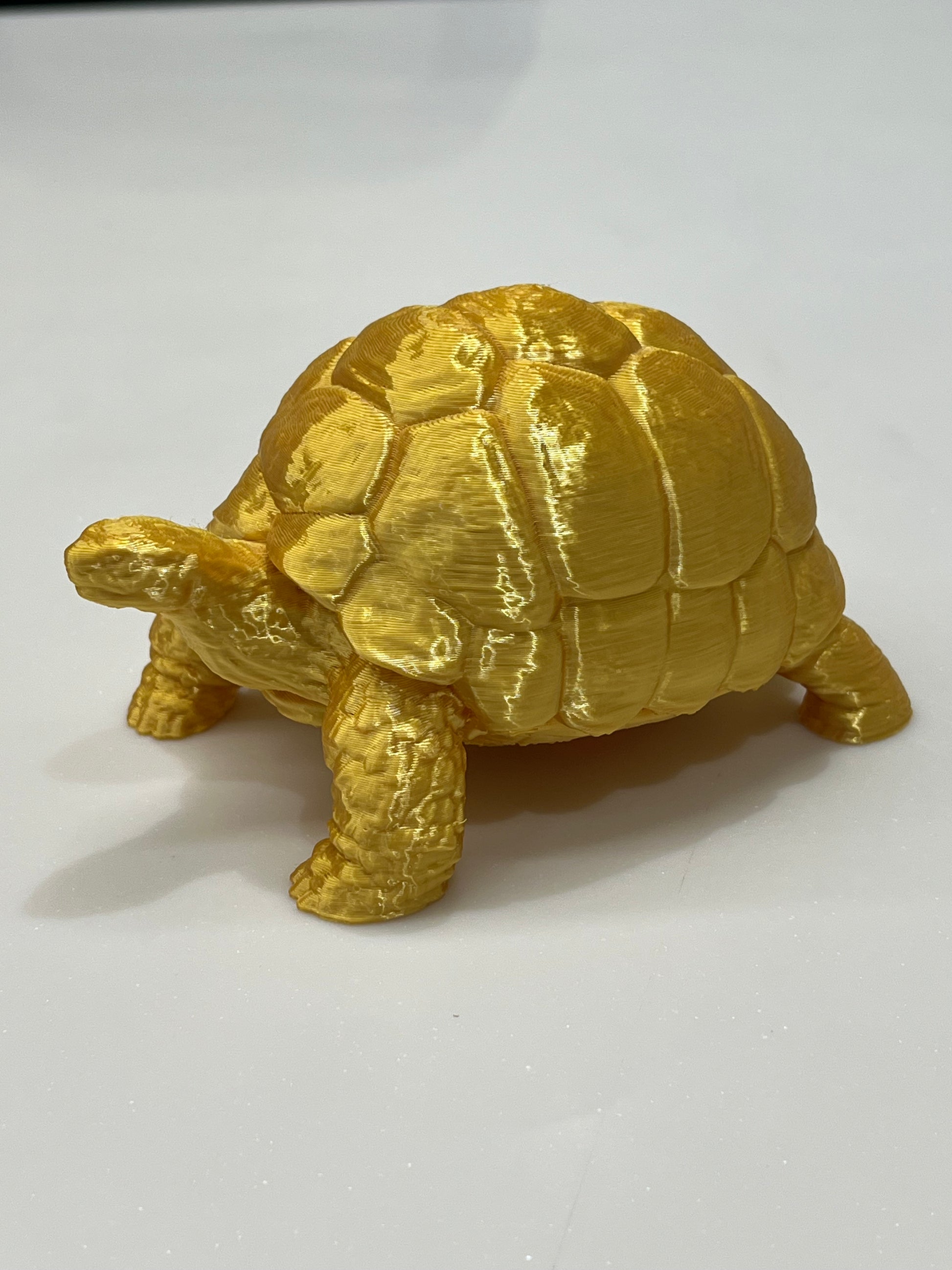 The Golden Vastu Tortoise - 5 Inch Prosperity & Stability Symbol, a gold-colored 3D-printed figurine with detailed shell and legs, rests on a white surface—an emblem of prosperity in Vastu Shastra.