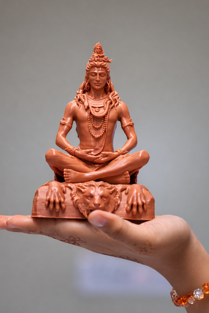 A hand holds the Lord Shiva Meditation Statue - 6.5 Inch Spiritual Energy Symbol, featuring intricate jewelry and a lion-faced base—an ideal addition to home temple décor, radiating spiritual energy against a softly blurred background.