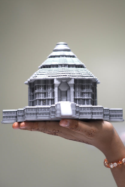 A hand adorned with henna holds the 5.5-inch Konark Sun Temple Sculpture, a detailed gray miniature model celebrating Indian architectural heritage against a plain background.