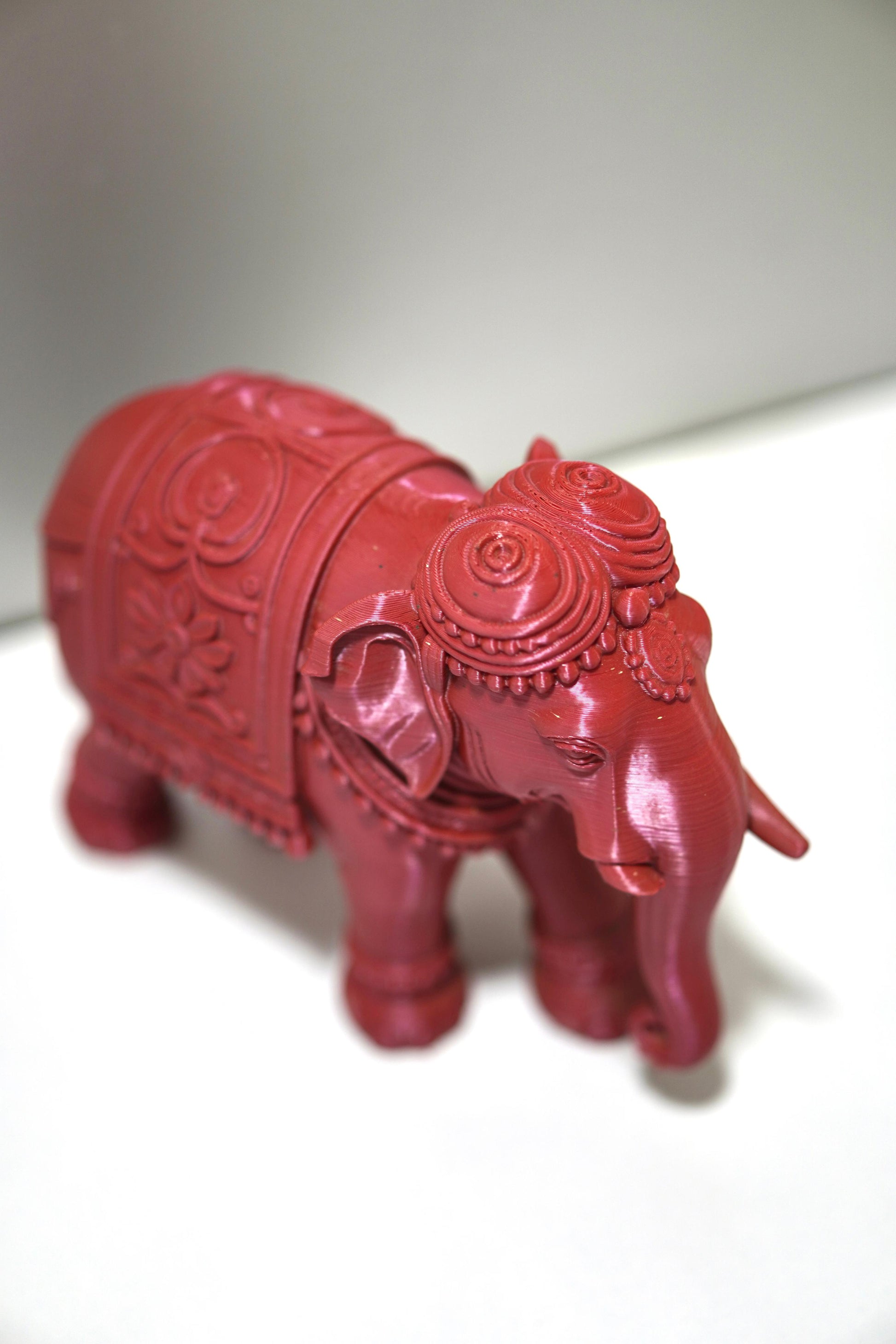 The Royal Prosperity Elephant - 6 Inch is a small, intricately carved red statue with decorative patterns, placed on a white surface against a light background—an elegant symbol of prosperity.