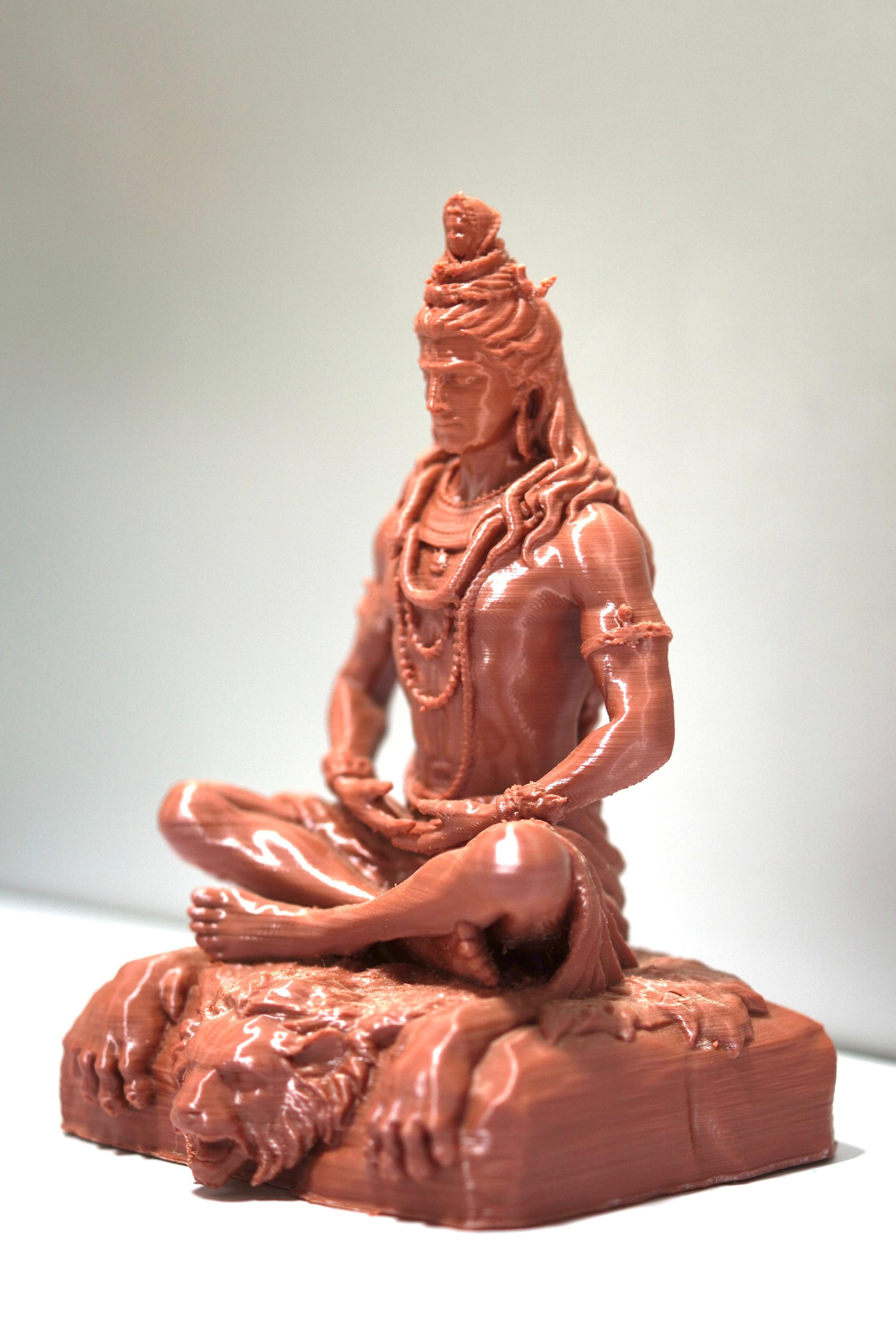 The Lord Shiva Meditation Statue (6.5") in brown, 3D-printed and cross-legged on a tiger skin base, radiates spiritual energy—perfect as home temple decor, especially against a simple light background.